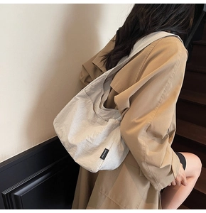 Detail of a minimalist off-white pleated fabric tote bag with a woven SHUNUO brand label
