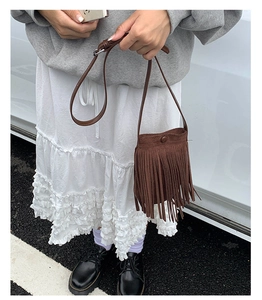 Gros plan d'un sac bandoulière en daim marron foncé avec de longues franges bohèmes