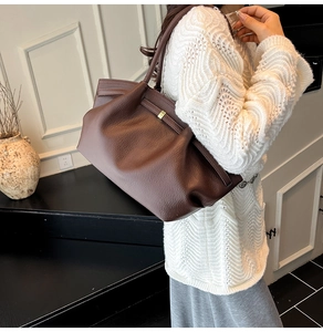 Close-up of deep brown lychee grain leather tote bag with pleated design and metal hardware