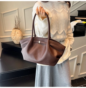 Close-up of dark brown lychee leather tote bag with pleated detail and gold hardware