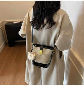 Détail du sac seau en toile avec bordure en cuir noir, boucle dorée et peluche