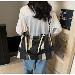 Close-up of black and white striped canvas travel bag with leather patchwork and logo