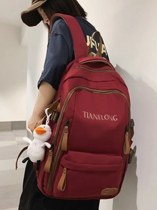 Large burgundy minimalist backpack with cute duck pendant shown on a model