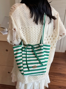 Green and white striped canvas tote bag with bow tie detail shown on female model