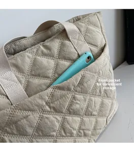 Detail of beige quilted tote bag showing a convenient front pocket with a blue smartphone