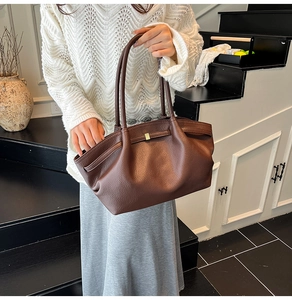 Detail of dark brown lychee leather texture and golden clasp on the pleated tote bag