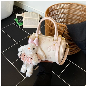 Detail of off-white leather pillow bag with pink bear embroidery and plush rabbit charm