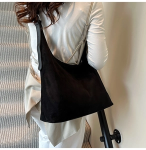 Macro shot of large black suede hobo tote bag texture and adjustable strap detail