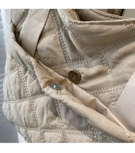 Detail view of the metal magnetic clasp closure on the quilted beige tote shoulder bag