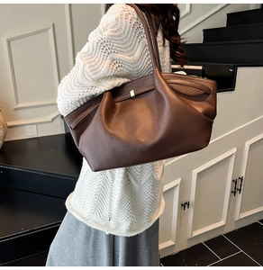 Close-up of dark brown lychee grain leather handbag with elegant pleated drop design