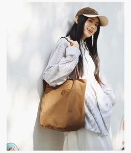 Detail of a brown large capacity tote bag with soft pleated fabric on a model