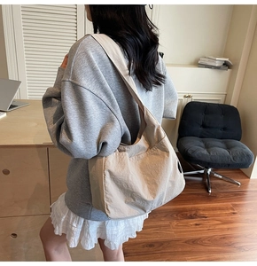 Detailed side view of a large khaki canvas tote bag worn over the shoulder for daily commute