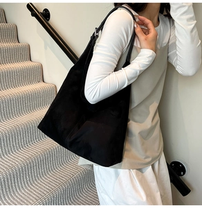 Detail view of large black suede tote bag with adjustable metal buckle on shoulder strap