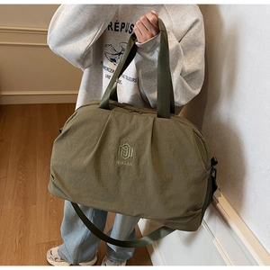 Detailed texture of olive green nylon travel bag with brand embroidery and strap