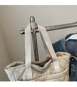 Detail of beige quilted tote bag showing reinforced stitching on the durable shoulder strap