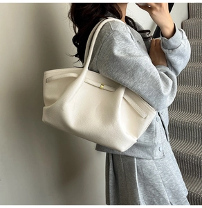 Close-up of off-white pebble leather tote bag featuring a minimalist gold metal buckle