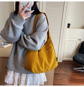 Close-up of bright yellow canvas hobo bag with wide shoulder strap on a model