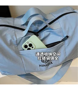 Close-up of light blue travel bag featuring front zipper pocket and durable nylon fabric