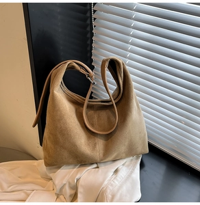 Detailed close-up of vertical stitching on the camel suede hobo shoulder bag