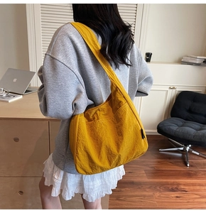 Close-up of a large ginger yellow nylon tote bag with front pocket and side label detail
