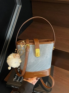 Sac seau en denim bleu et cuir marron avec pendentif agneau en peluche sur escalier