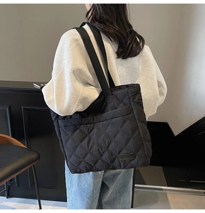 Side view of a quilted black tote bag on a model showing large capacity and soft texture