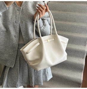 Detail of white lychee texture leather tote bag with gold metal trim on model
