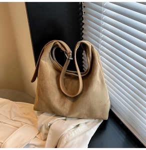 Detail of camel suede tote bag with vertical stitching and adjustable leather strap