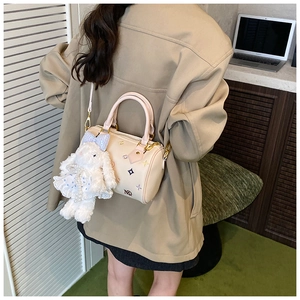 Detail view of beige pillow bag featuring colorful floral embroidery and cute rabbit charm