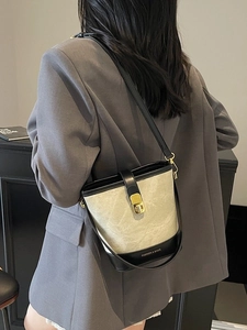 Sac seau bicolore beige et noir avec fermoir doré porté en bandoulière stylée
