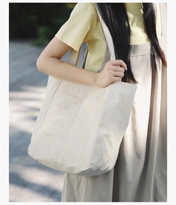 Detailed macro view of a beige minimalist tote bag showing the crinkle nylon texture