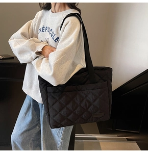 Close-up of black quilted nylon tote bag showing diamond stitching and shoulder strap