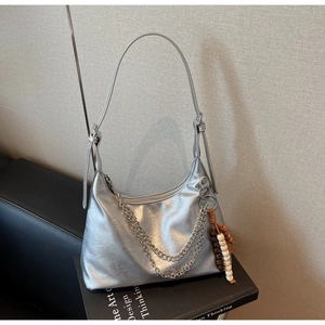 Close-up of metallic silver underarm bag with double metal chains and beaded charm detail