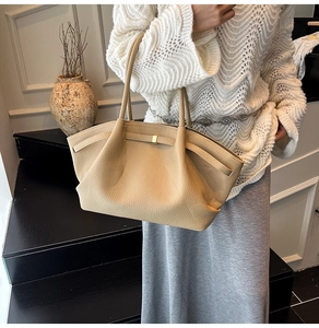 Detail of pleated beige leather tote bag with lychee texture and slim top handles