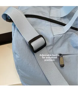 Detail of adjustable shoulder strap and plastic buckle on light blue nylon travel bag
