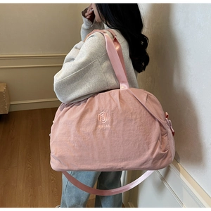 Detailed close-up of pink pleated fabric travel bag with embroidered logo and mesh pocket