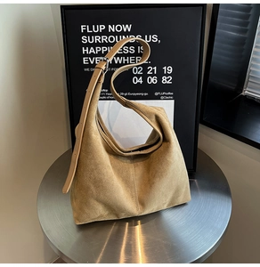 Detail of adjustable strap and brushed metal buckle on light camel suede hobo bag