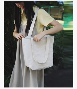 Outdoor shot of a minimalist large off-white canvas tote bag with front pocket detail