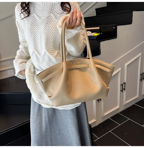 Detail of beige hobo tote bag with textured pebbled leather and elegant buckle closure