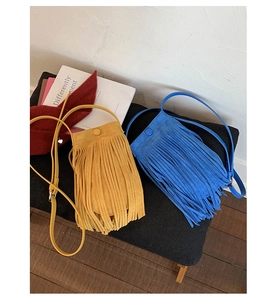 Sacs à bandoulière jaunes et bleus avec franges et bretelles réglables sur banc
