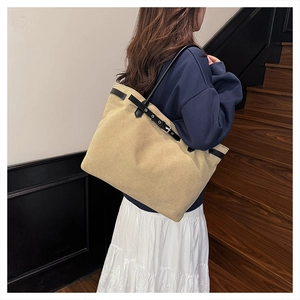 Detail of khaki canvas tote bag with black leather trim and metal buckle on stairs