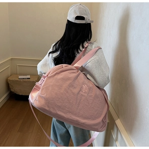 Pink large capacity travel bag with wide shoulder strap shown carried by a model