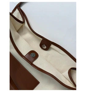Detail of canvas tote bag showing magnetic snap closure and leather inner pocket