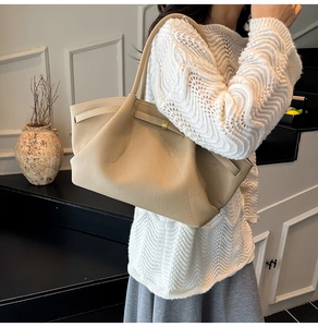 Detail of beige pleated tote bag featuring a gold metal buckle and premium litchi texture