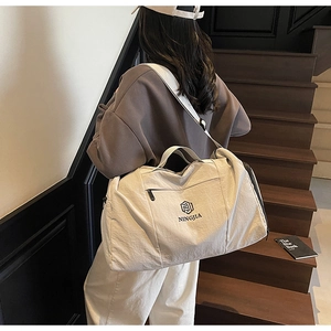 Detailed view of beige travel bag with NINGJIA logo and adjustable wide shoulder strap