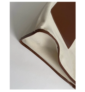 Detailed close-up of premium canvas tote bag showing caramel leather stitching and seams
