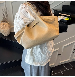 Close-up of beige lychee grain leather tote bag with elegant pleats and metal buckle detail