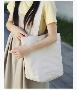 Detail of minimalist beige canvas tote bag side pocket with aesthetic outdoor model view