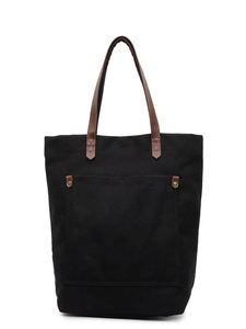 Minimalist black canvas tote bag with brown leather handles and front pocket with rivets