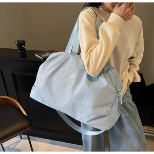 Detail of light blue waterproof travel bag with logo and detachable shoulder strap